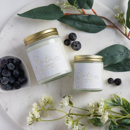 Diffuser une ambiance estivale avec une bougie parfumée en cire de soya biologique aux notes de bleuets et vanille, offerte avec mèche de bois ou coton.
