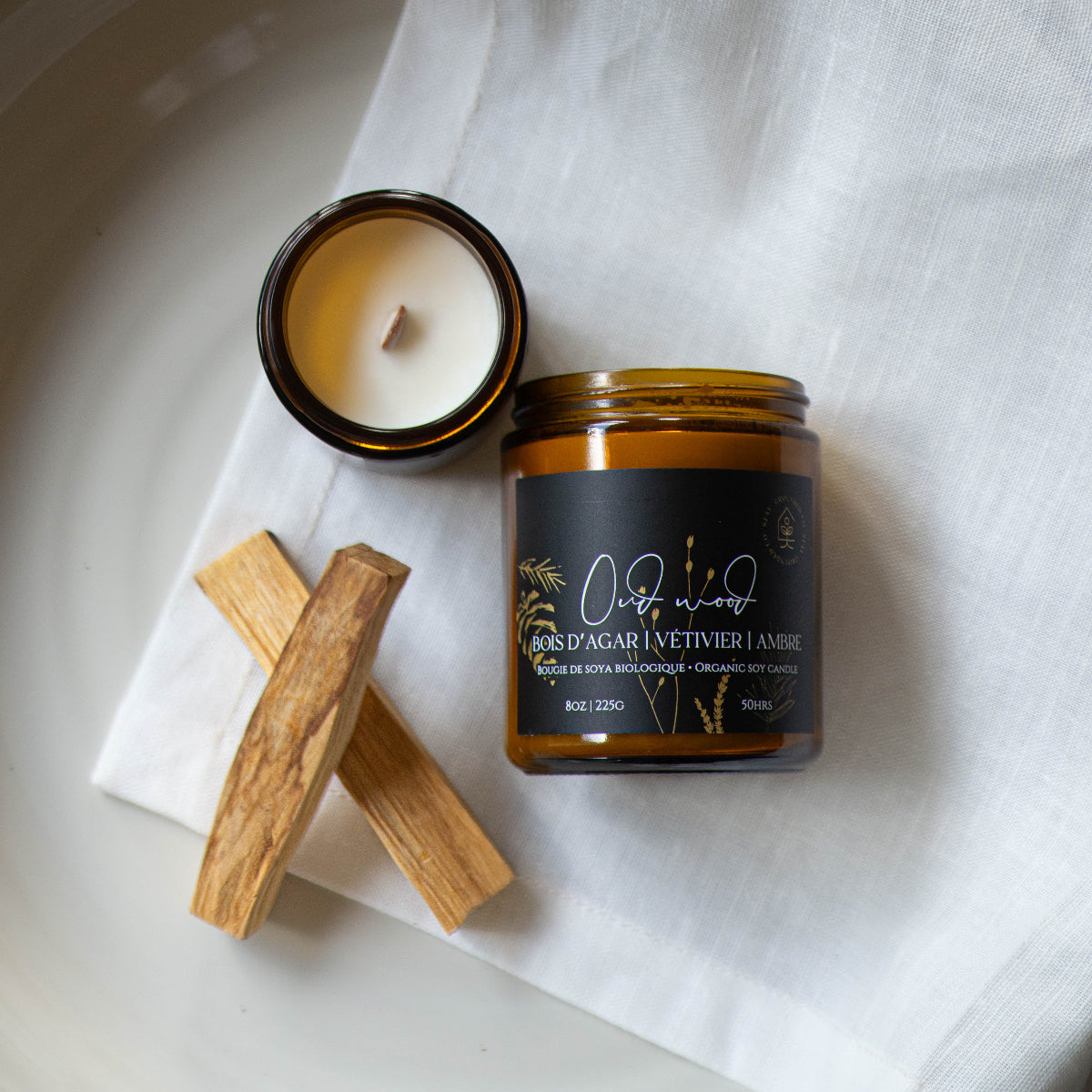 Diffuser une ambiance sophistiquée avec une bougie parfumée en cire de soya biologique aux notes de bois d'agar et ambre, offerte avec mèche de bois ou coton. vue 2.